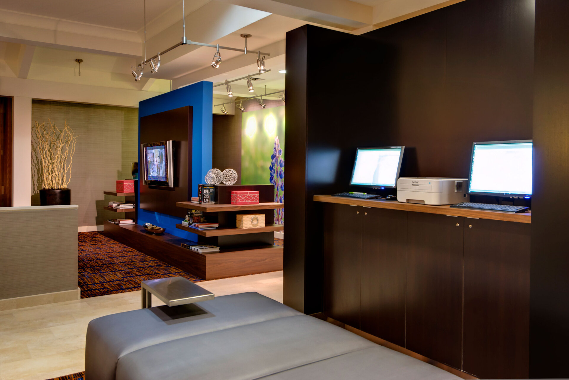 A hotel lobby with a business center, seating area, and reception desk.