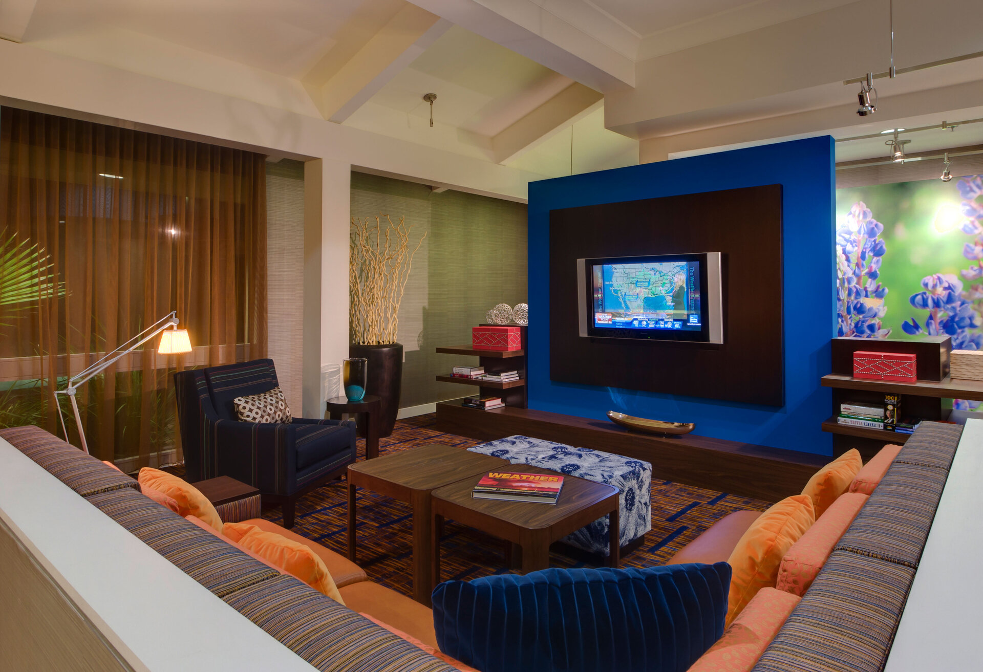 A hotel lobby seating area with a sofa, coffee table, TV, and armchair.