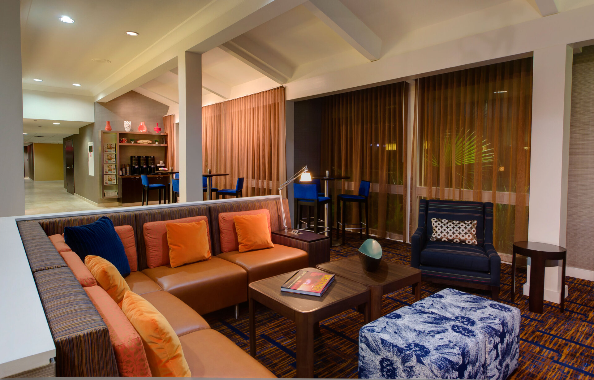 A hotel lobby seating area with a sofa, armchair, coffee table, and ottoman.
